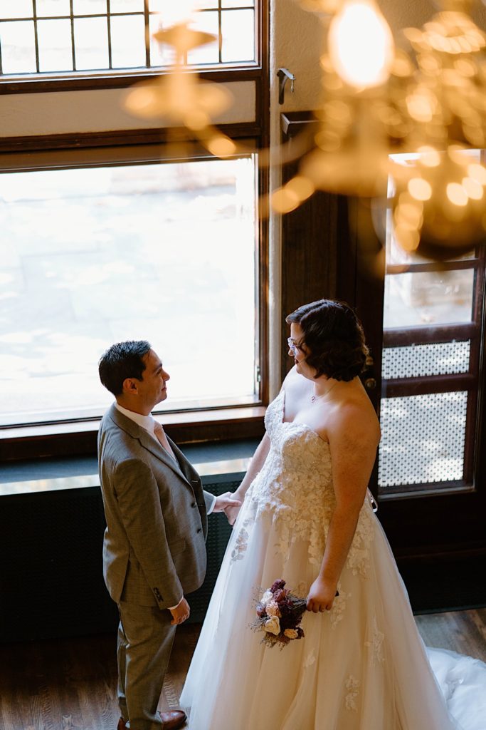A bride and groom share a first look in the main room of the Grove Redfield Estate.