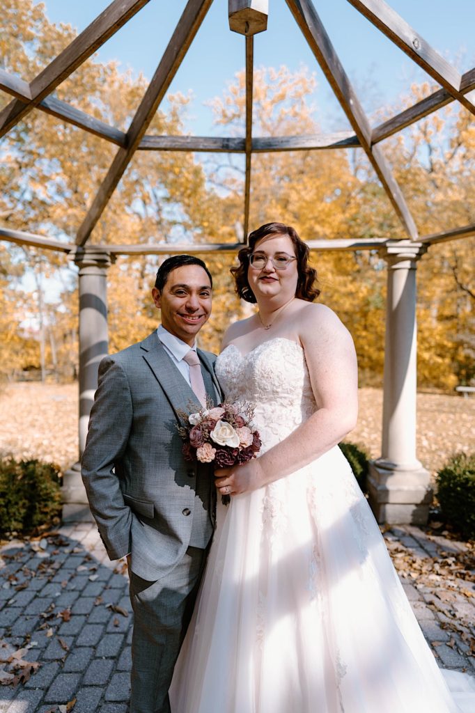 The bride and groom taking their wedding portraits under the gazebo at the Grove Redfield Estate.
