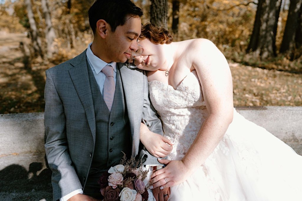 A bride and groom sit together at the Grove Redfield Estate in the fall after their elopement ceremony.