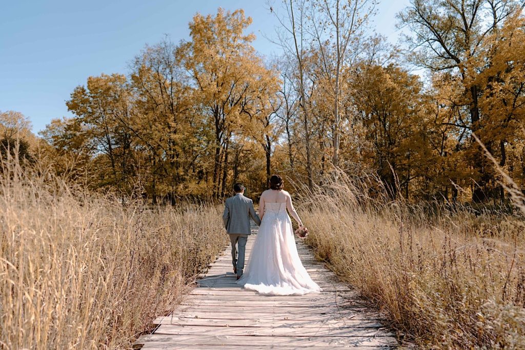 A bride and groom walk through the Grove Redfield Estate in the fall after their elopement ceremony.