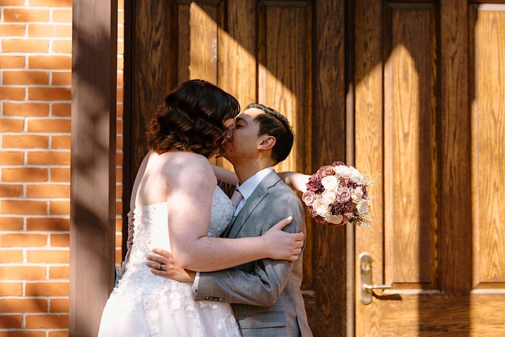 A bride and groom stand in front of the Grove Redfield Estate in the fall after their elopement ceremony.