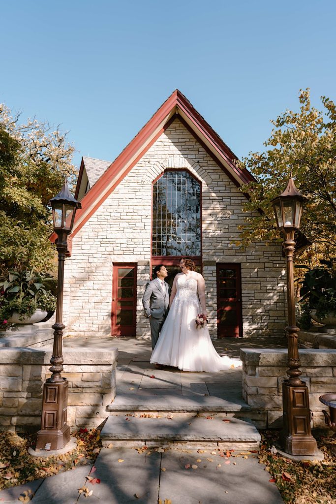 A bride and groom stand in front of the Grove Redfield Estate in the fall after their elopement ceremony.