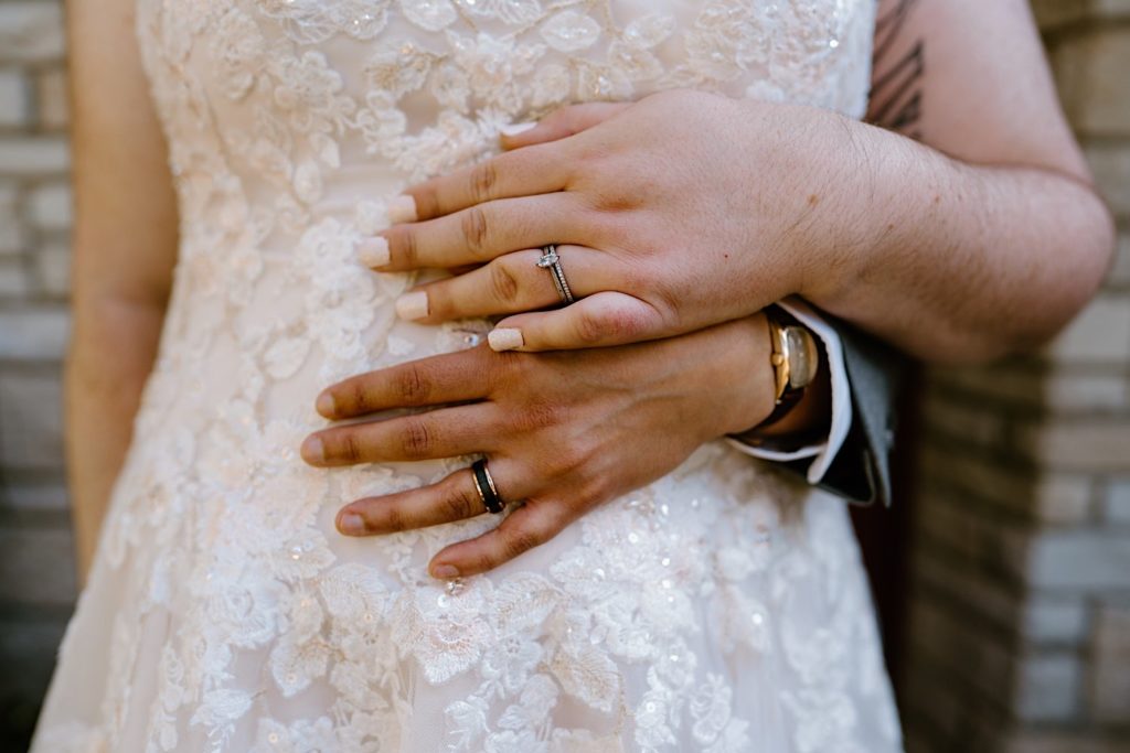 The bride and groom show off their wedding rings while holding one another after their Chicago wedding.