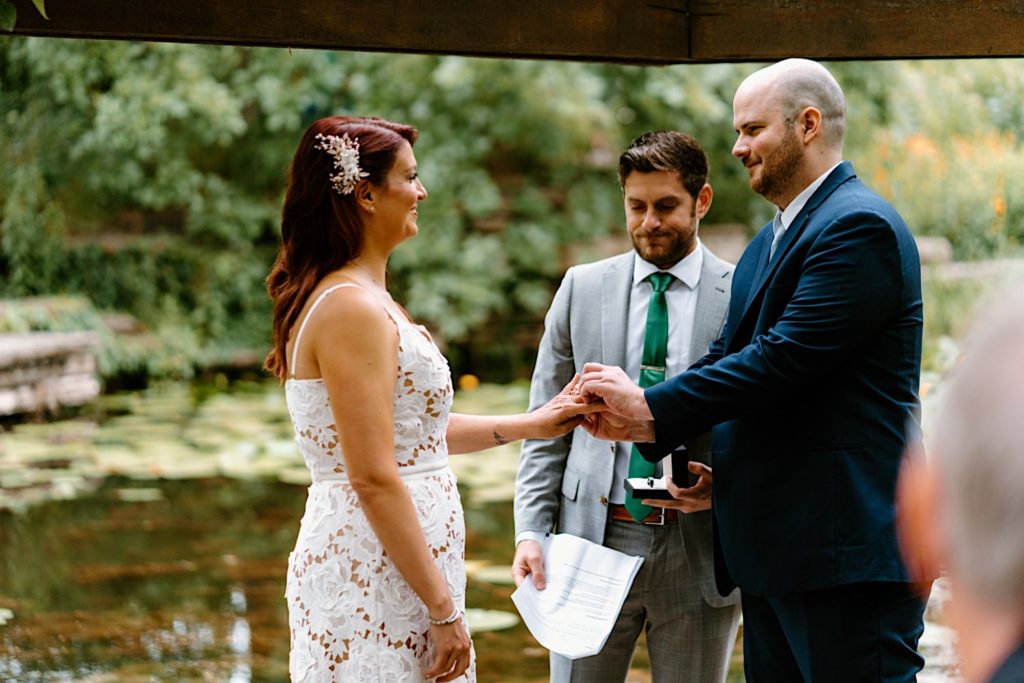 A bride and groom smile at one another during their elopement in Chicago at the Alfred Caldwell Lily Pool.