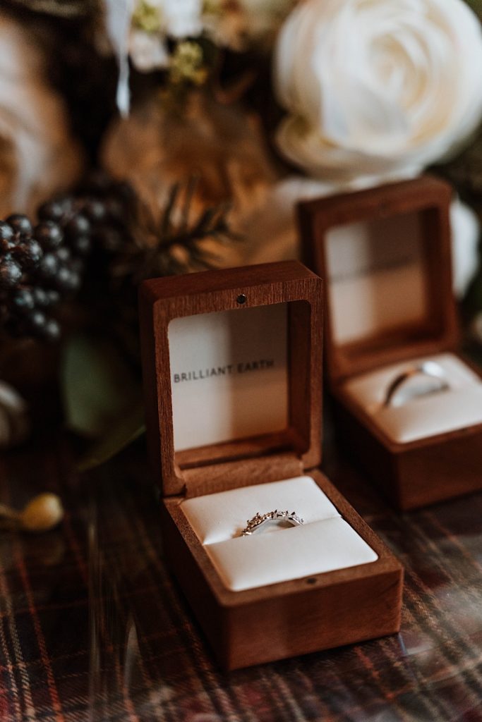 A Brilliant Earth wedding ring in a wooden ring box sitting on a bed before an elopement.