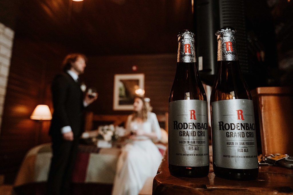 The couples favorite beer sitting on a table while they are in the background enjoying the beers.