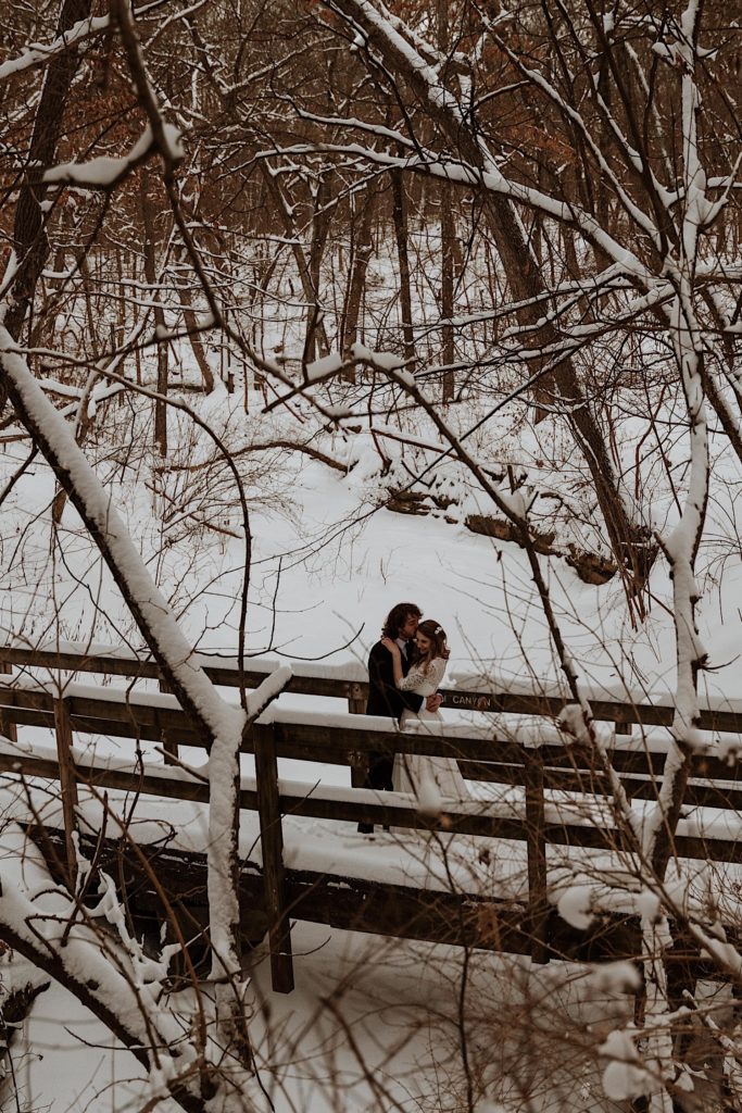 A bride and groom snuggle in close while standing on a bridge in Starved Rock National Park.