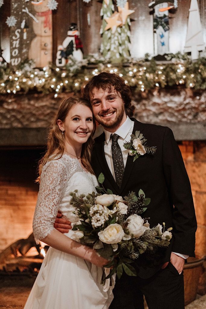 A bride and groom smile at the camera standing in front of the fireplace after taking their wedding portraits at Starved Rock National Park.