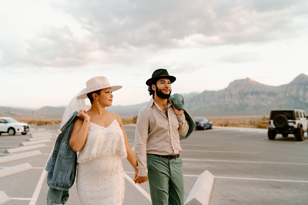 A bride and groom walk together holding hands in the parking lot after their elopement in Moab.