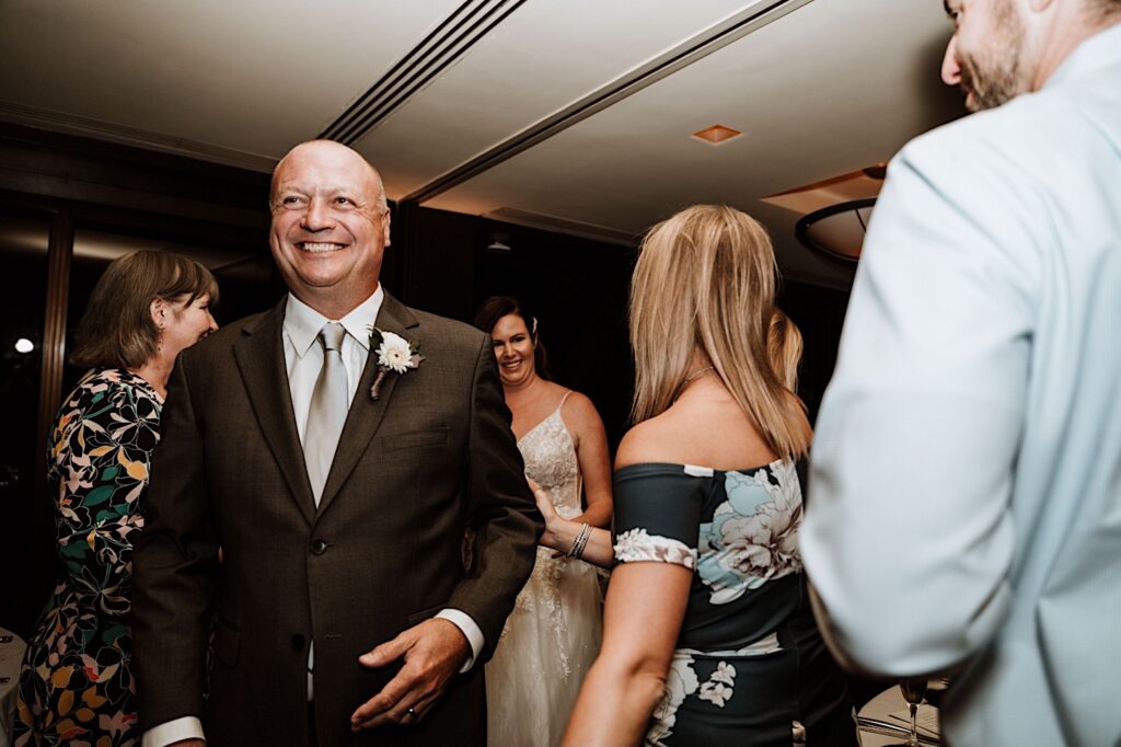 The groom smiles and walks away from guests.