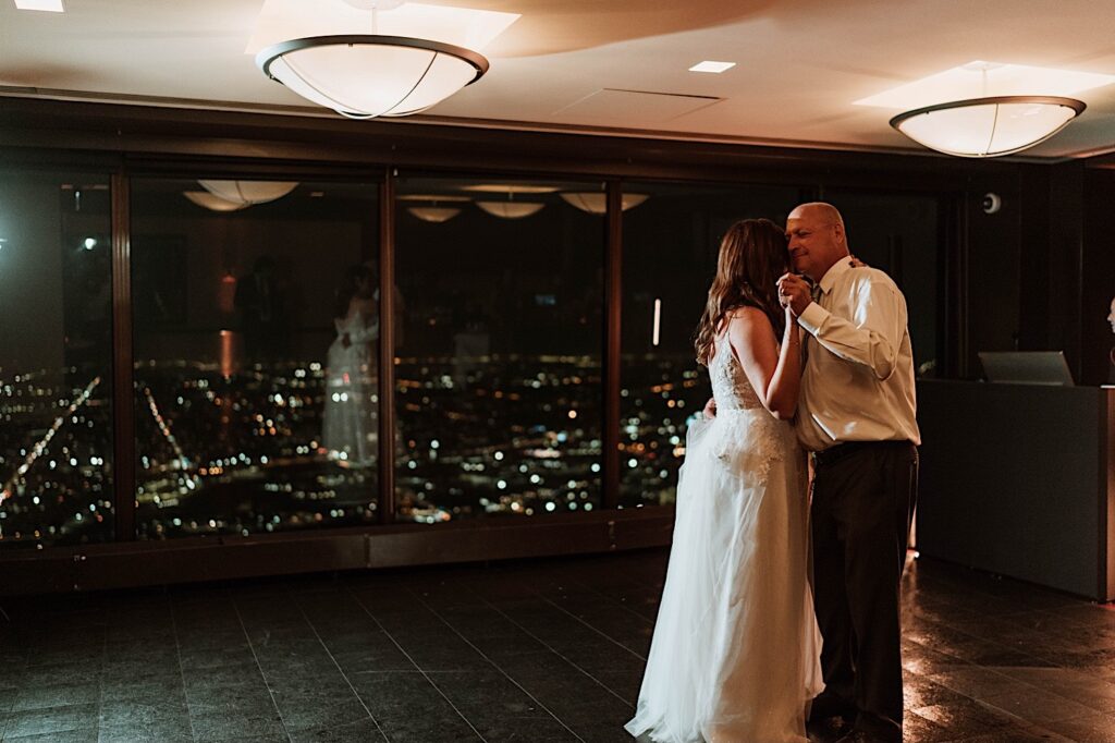 A bride and groom have their first dance overlooking the Chicago night time sky.