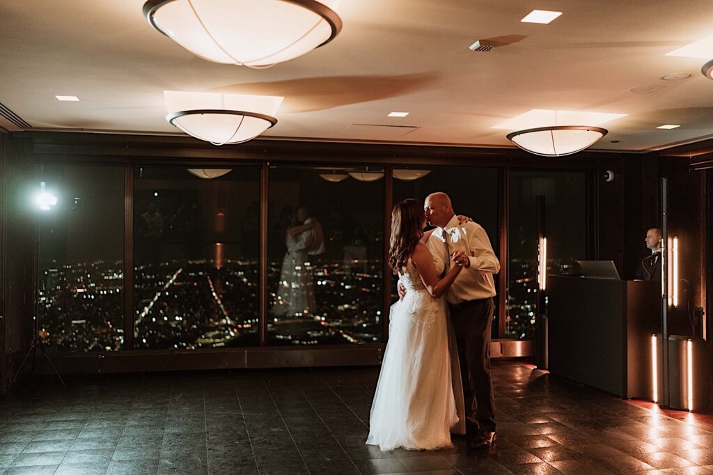 A bride and groom have their first dance at the Signature Room on the 95th floor.