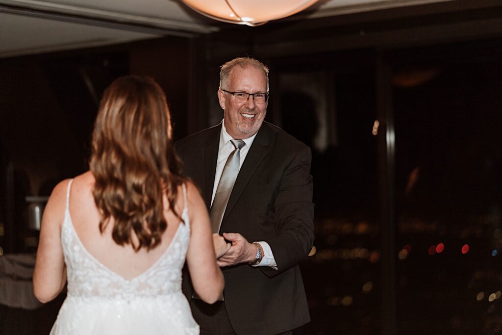 A bride and her father have their first dance at the Signature Room on the 95th floor.