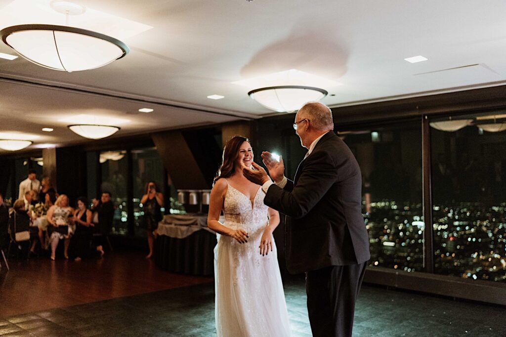 A bride and her father have their first dance at the Signature Room on the 95th floor.