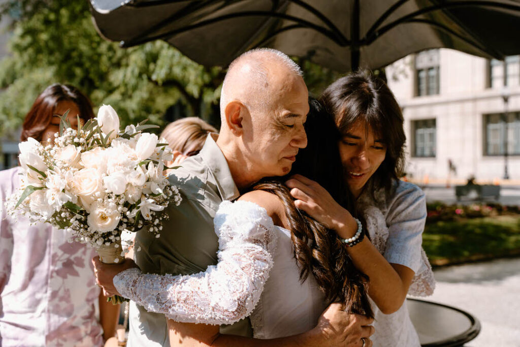 the bride's father and brother hugging the bride