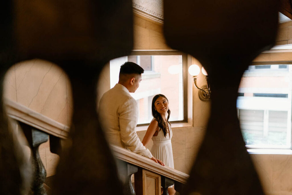 bride and groom walking down the stairs and the woman is looking back at her husband - chicago city hall elopement