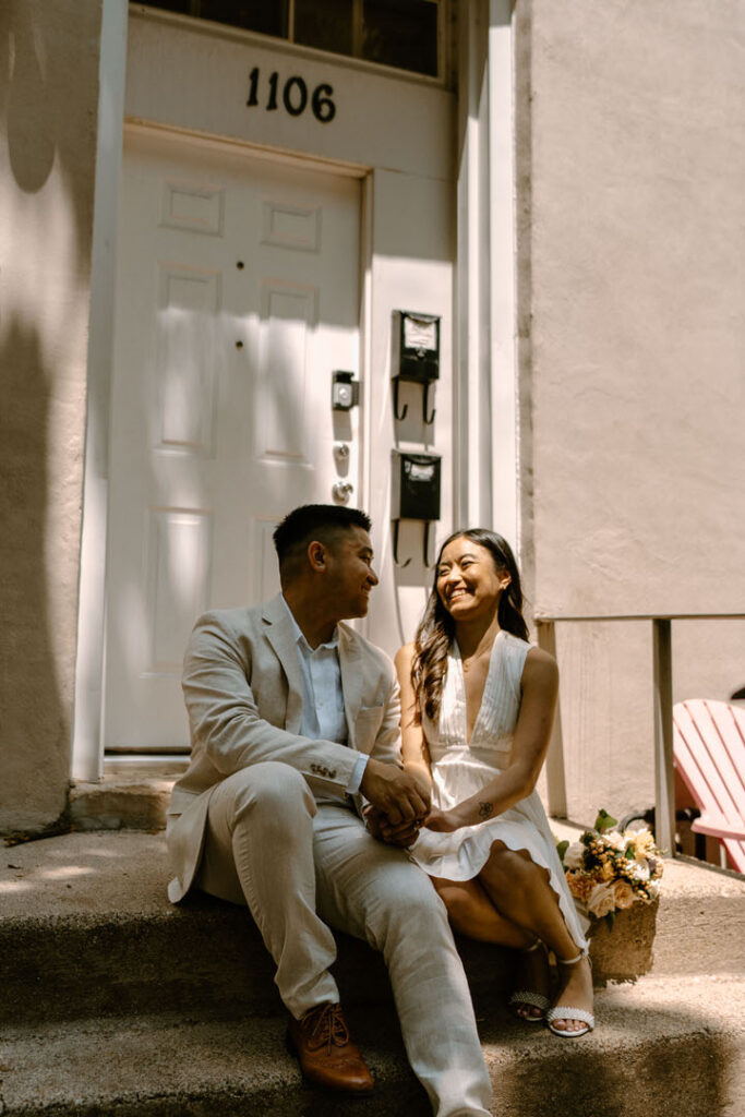 two people sitting on the front steps of an apartment laughing